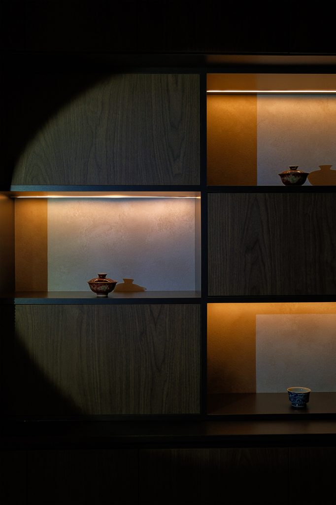 Warmly lit tea house shelves showcasing Chinese tea culture with delicate teacups, highlighting the rich history, beauty, and relaxing tradition of tea appreciation.