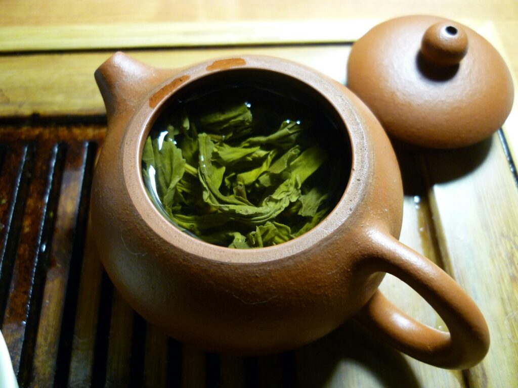 Green Tea Leaves : A teapot filled with freshly brewed green tea, releasing delicate steam and subtle grassy aromas that evoke calm and tradition.