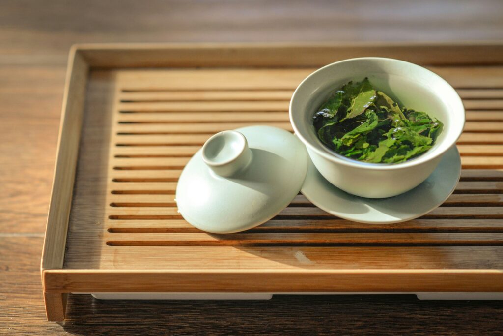 An array of various green tea leaves is displayed, showcasing shapes, sizes, and colors, highlighting the unique characteristics of the camellia sinensis plant. This arrangement emphasizes the beauty and variety found in green teas, which are known for their many health benefits and antioxidant properties.