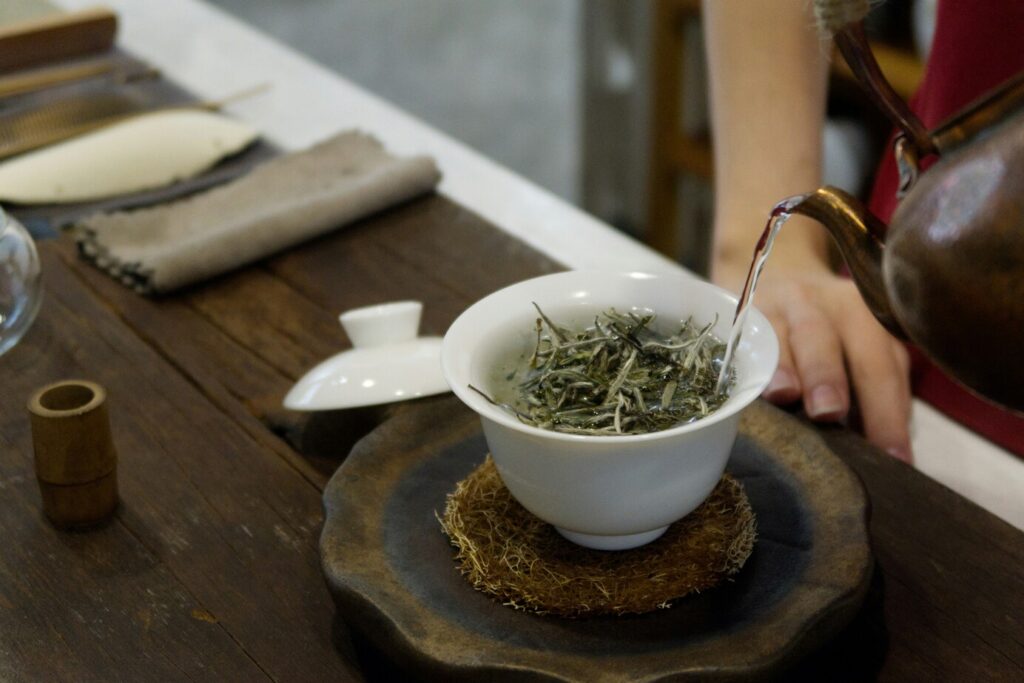 Tea Tasting Guide : A tea master pouring golden oolong tea into small porcelain cups.