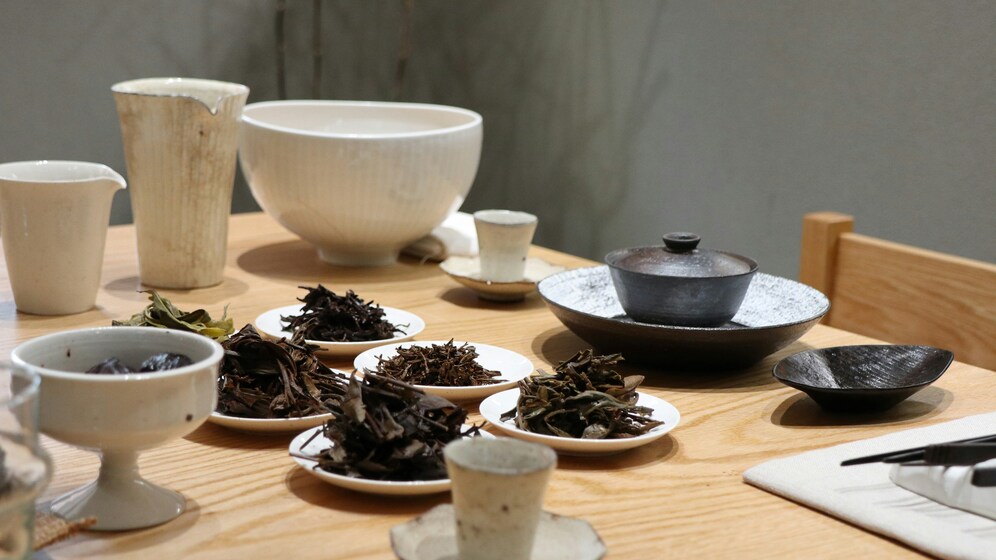 Pu erh tea : Loose pu erh tea leaves scattered on a wooden table, showcasing their deep earthy tones and rich texture.