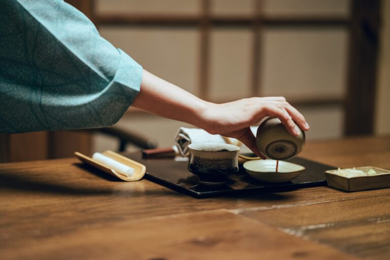 A traditional Chinese tea ceremony where a host gently pours hot tea from a clay teapot into delicate porcelain cups, capturing the calm, graceful flow of the ritual