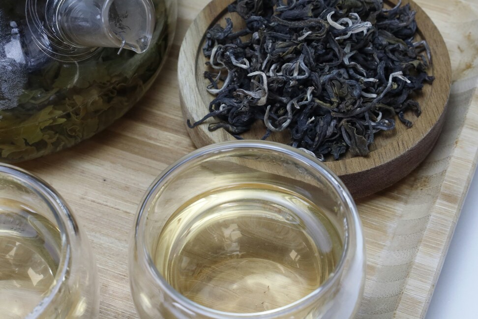 A detailed close-up shot of pristine white tea leaves alongside a cup of brewed tea, emphasising the freshness and quality of the ingredients