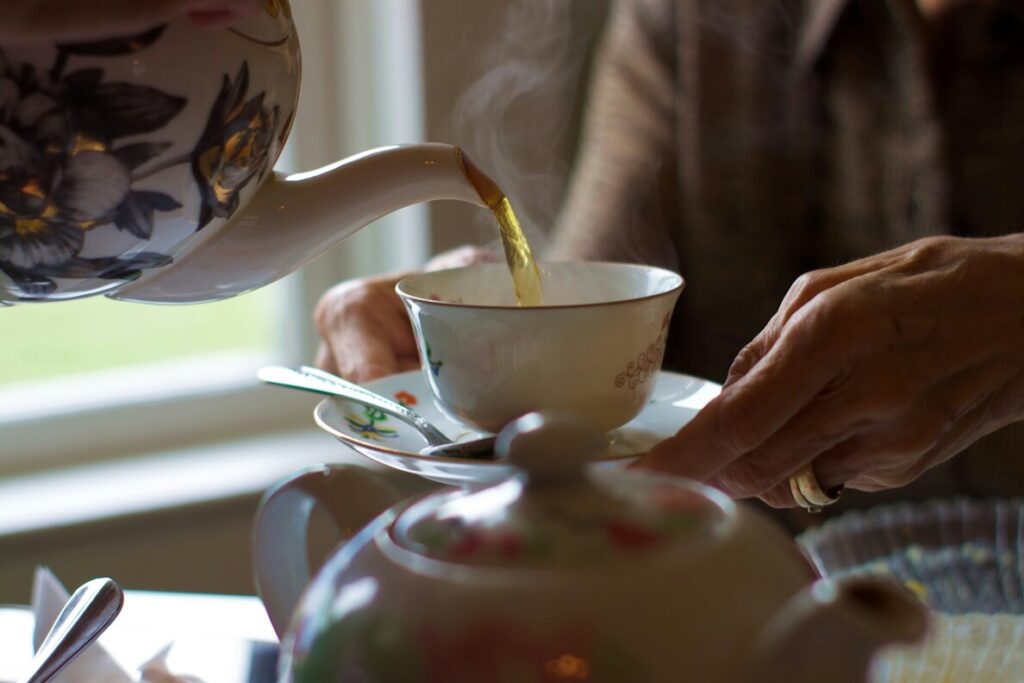 A Western-style tea ceremony featuring porcelain teacups, a flower teapot, and pastries arranged on a refined table setting
