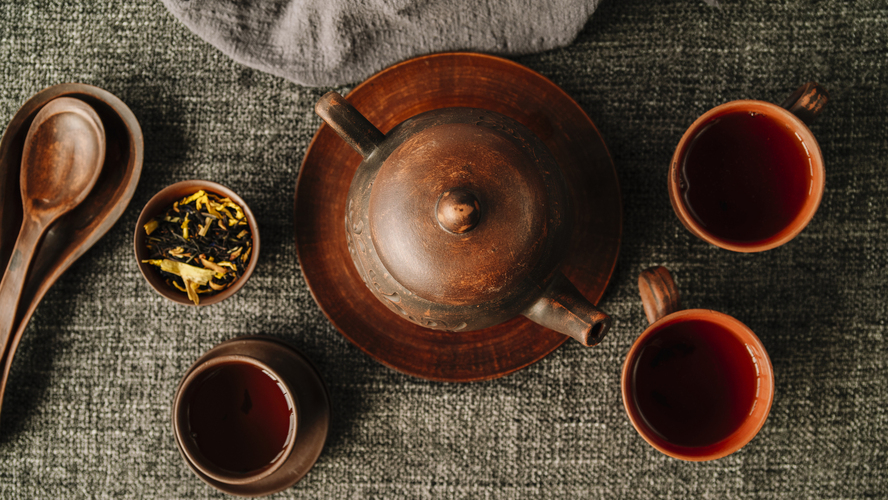 pu erh tea caffeine : A complete tea set displayed on a wooden table with teapot, cups, and tea leaves, evoking a serene brewing ritual.