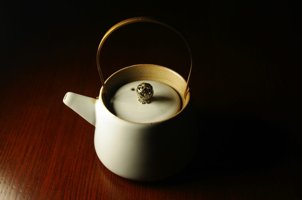 A ceramic teapot placed beside a cup of steaming tea, capturing the essence of a peaceful tea ritual.