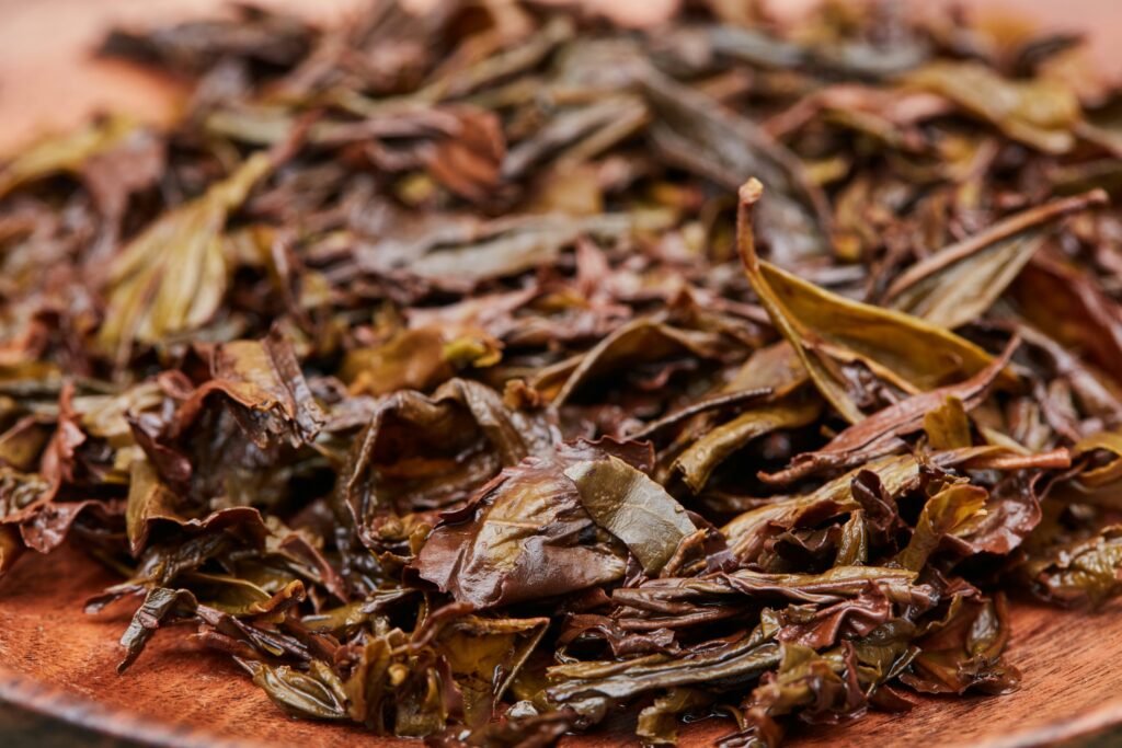 A single high-quality tea leaf resting on a wooden tray, symbolising purity and simplicity, captured alongside elements of a Zen-inspired tea ceremony setting