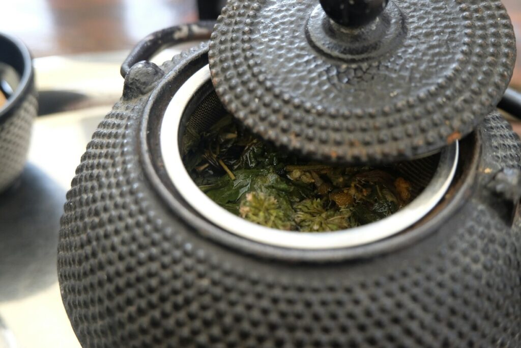Delicate tea leaves floating gracefully inside a teapot, reflecting the purity and artistry of fine tea preparation.