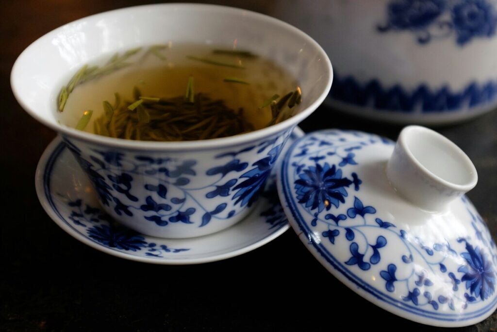 A warm cup of tea with a fresh tea leaf floating gently on the surface, symbolising calm and tradition.