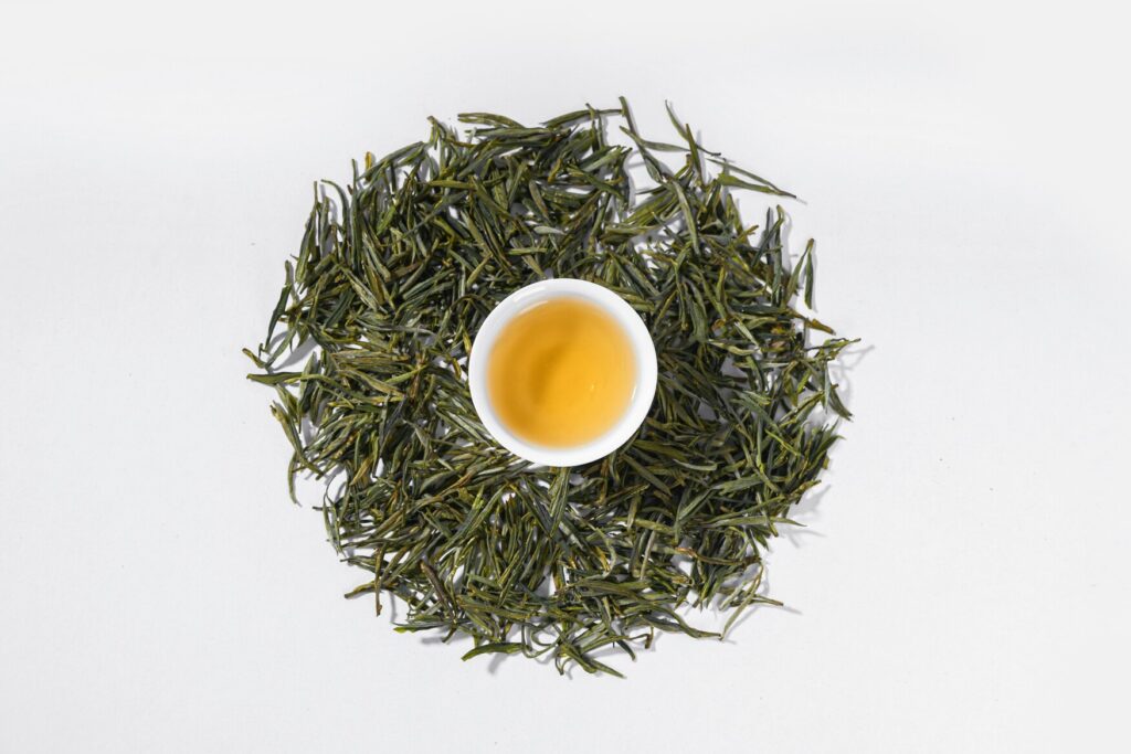 Green Tea : Premium Chinese green tea leaves steeping in crystal-clear water, revealing vibrant colour and clarity.