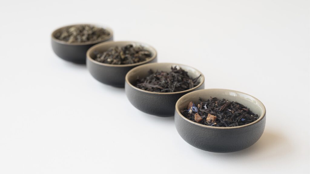 pu erh tea caffeine : Various dried pu erh tea leaves displayed on a wooden table, illustrating the different oxidation levels that influence caffeine.
