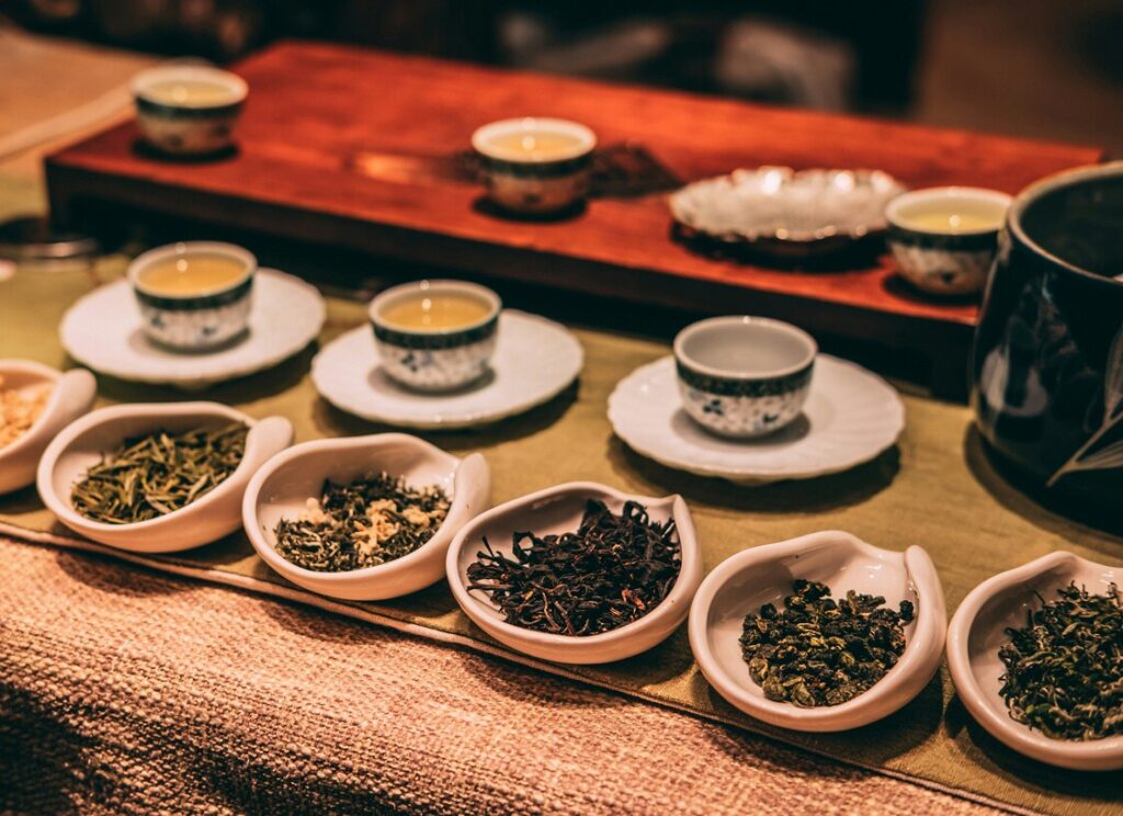 Various types of white tea displayed on a wooden tray, highlighting the subtle differences in colour and leaf shape.