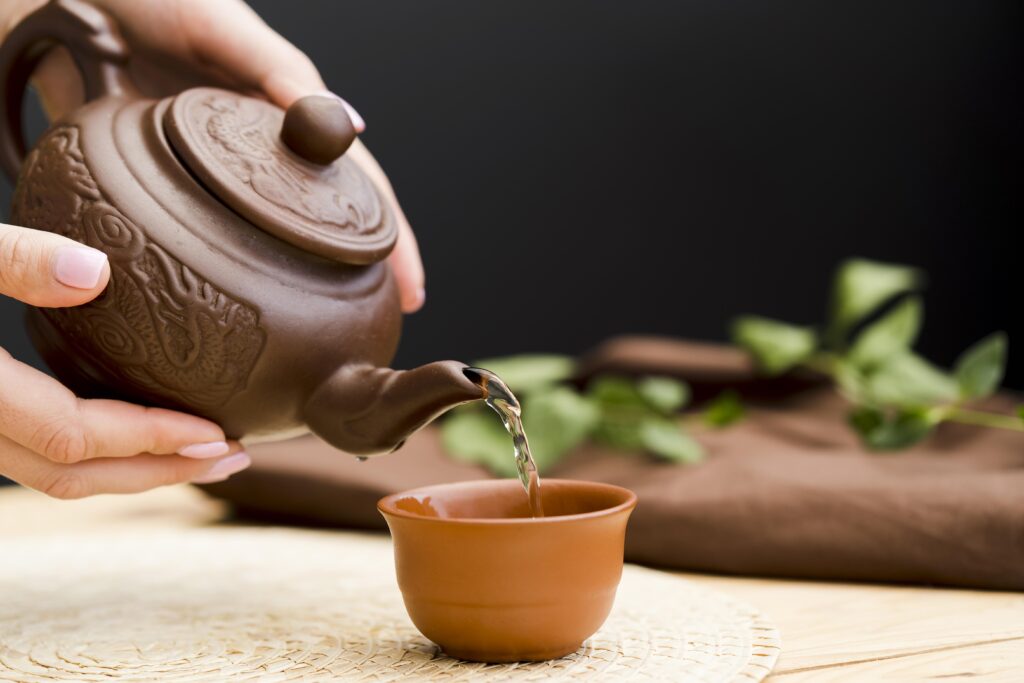 pu erh tea caffeine : Hot pu erh tea being poured gently into a porcelain cup, releasing aromatic steam that hints at its rich, earthy flavour.