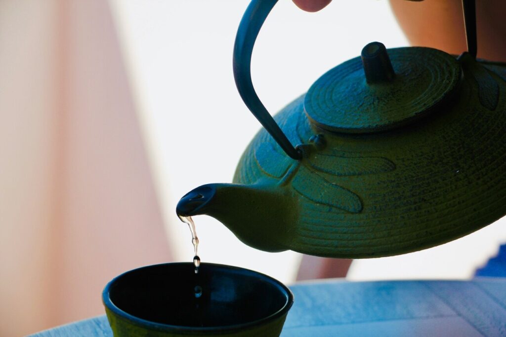 Tea being slowly poured into a teacup, emphasising grace, patience, and the fluid motion of traditional tea service
