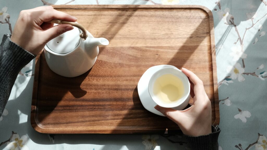 A graceful hand gently pouring freshly brewed tea, capturing the calm precision and mindful ritual of traditional tea preparation.