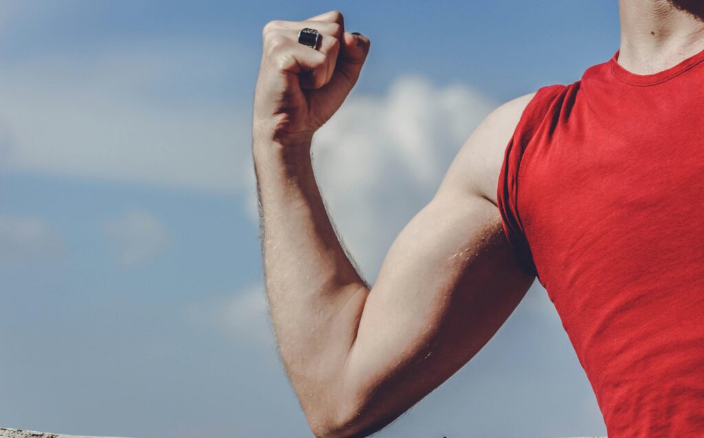 A man flexing his arm to show his bicep strength, symbolising a strong immune system and the benefits of maintaining a healthy, active lifestyle.