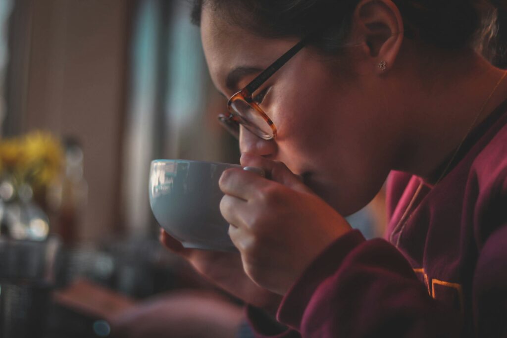 A woman calmly sipping Chinese tea, her expression relaxed as she savours the aroma and warmth of the brew.