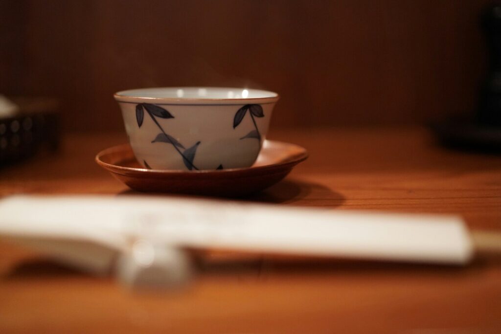 A minimalist shot of hot Chinese tea in a porcelain cup, showcasing its rich colour and gentle steam rising above