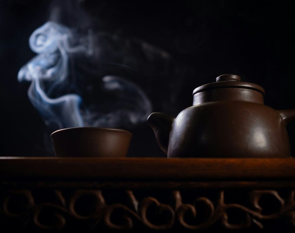 Hot water swirling inside a teapot and cups to warm the teaware before brewing, a key step in Chinese tea rituals