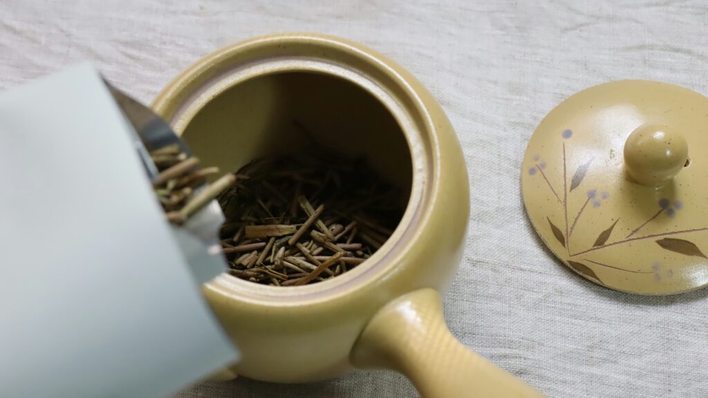 Loose tea leaves being gently placed into a teapot, highlighting the mindful ritual and precision behind a proper tea ceremony.