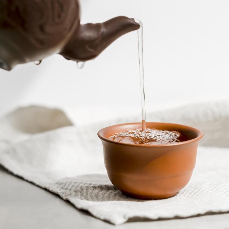 Fresh, clear water poured gracefully into a teacup, preparing for a clean and refined brew.