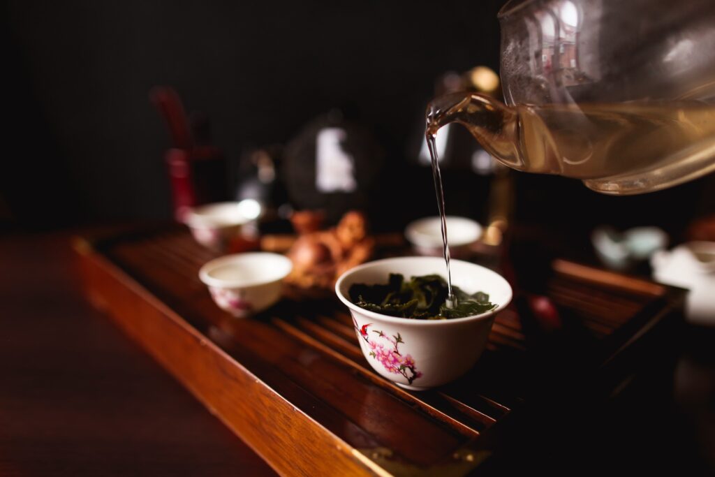 The image features a traditional Yixing teapot alongside aged pu-erh tea leaves, with several small cups arranged for gongfu brewing. This scene captures the essence of preparing tea, highlighting the loose leaf tea and the art of brewing to create the perfect cup of hot tea.