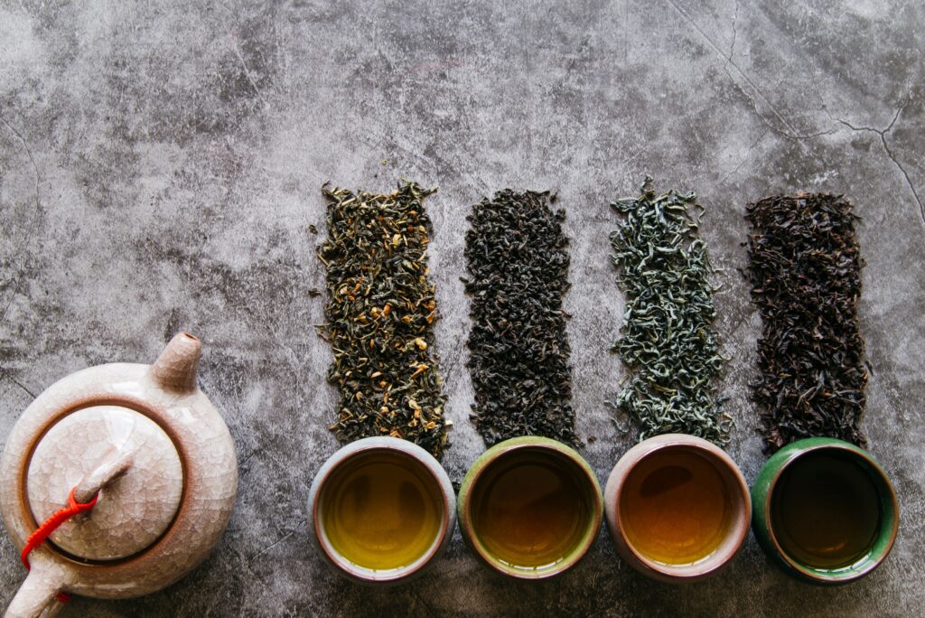 An assortment of Chinese tea leaves—green, oolong, black, and white—displayed side by side to show their unique shapes, colours, and textures.