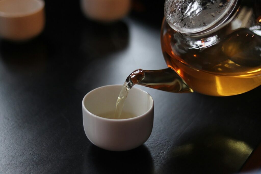 Freshly brewed tea being poured smoothly into a small teacup, highlighting colour, clarity, and aroma.