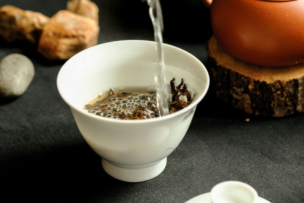 A stream of hot water being gently poured into a teacup, beginning the delicate process of tea infusion.