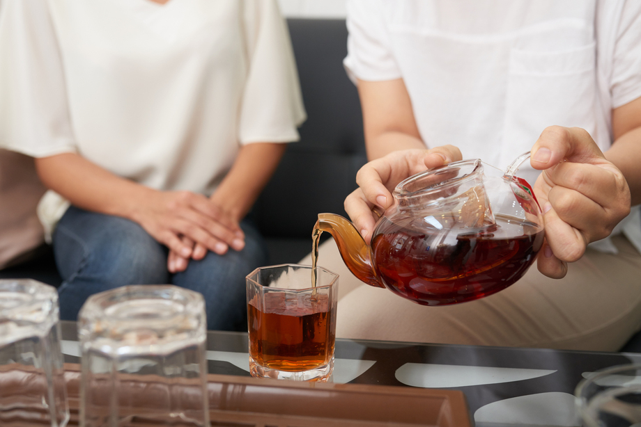 A graceful hand pouring freshly brewed black tea into a cup, capturing warmth, aroma, and a moment of quiet indulgence