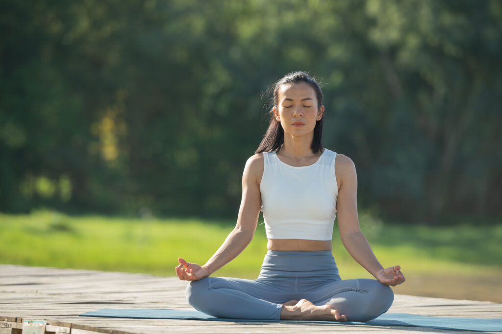 A woman sitting peacefully in a meditation pose, highlighting how calm breathing and mindfulness can support cardiovascular health and overall balance.