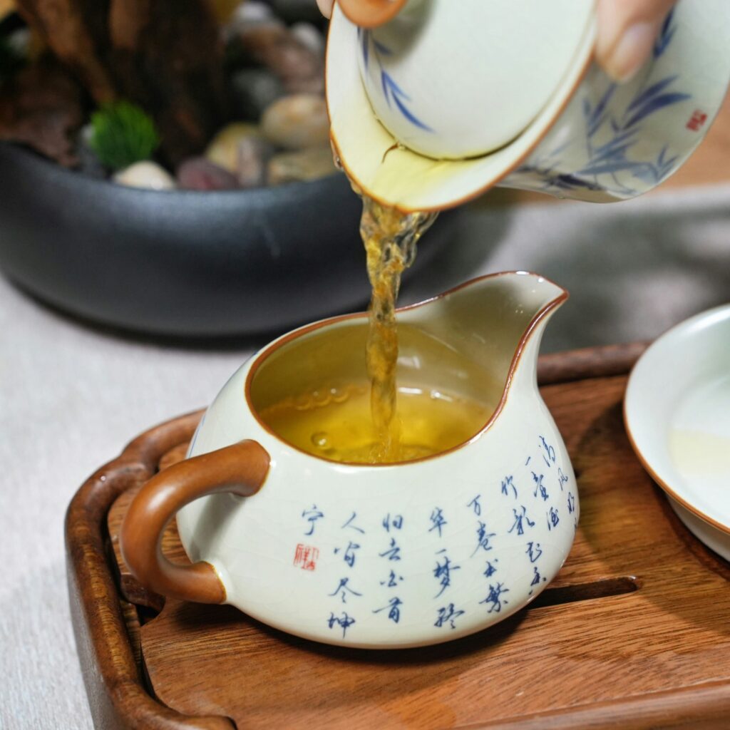 A close-up of a hand pouring green tea into a teacup, emphasising precision, warmth, and the art of mindful brewing.