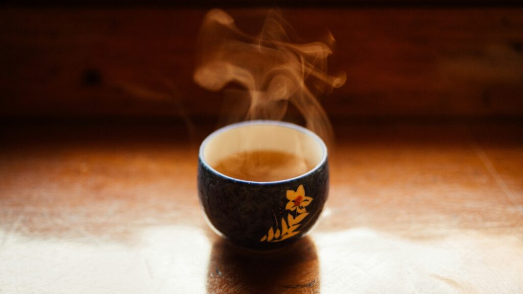 Freshly brewed tea served in a Chinese tea cup, revealing a soft jade hue that symbolises clarity, freshness, and calm.
