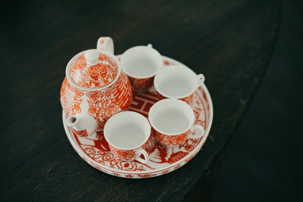A deep red Chinese tea cup set resting on a wooden table, symbolising warmth, celebration, and the richness of traditional tea rituals.