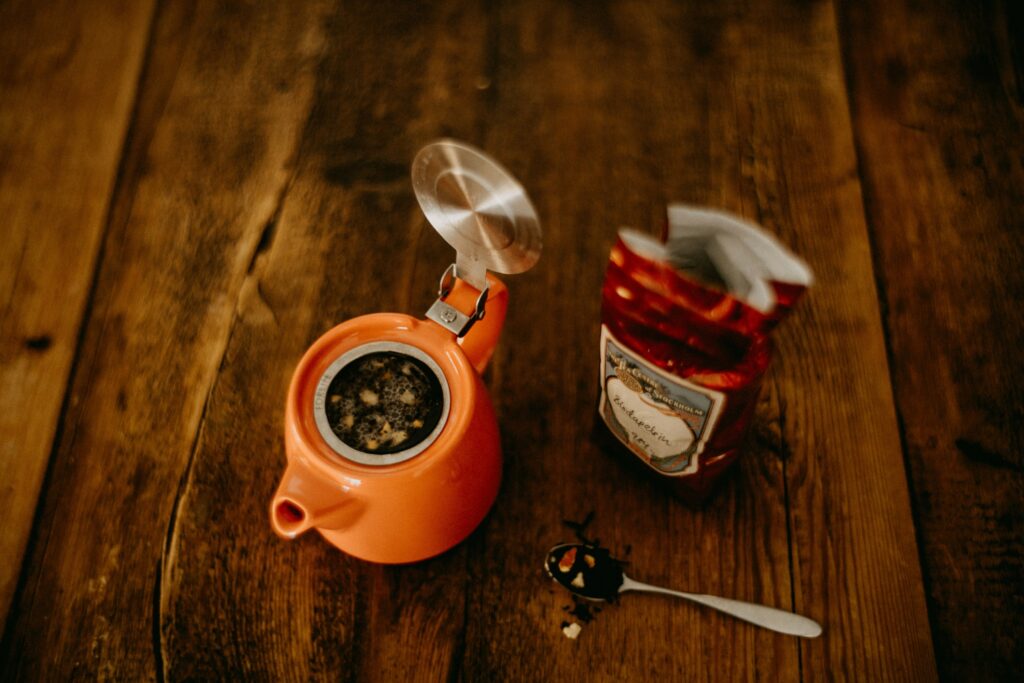 A modern tea bag package placed beside a small teapot, representing contemporary convenience while maintaining the comfort of traditional tea brewing.