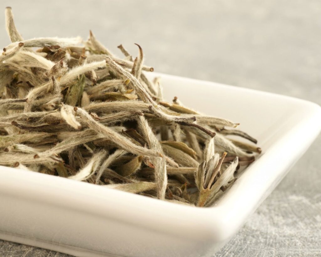 Delicate, pale tea leaves with fine silvery buds, gently dried with minimal oxidation to preserve their natural sweetness and soft floral aroma.