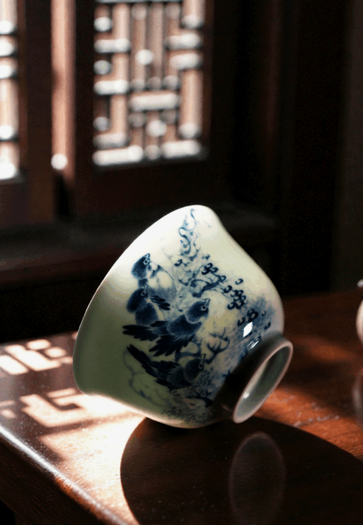 A Chinese teacup rests on a wooden table as warm sunlight streams across its surface, creating a peaceful and inviting tea scene.