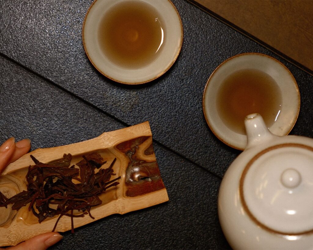 A close-up view of small teacups beside a teapot and scattered tea leaves, showcasing the intimate details of a Chinese tea setting.