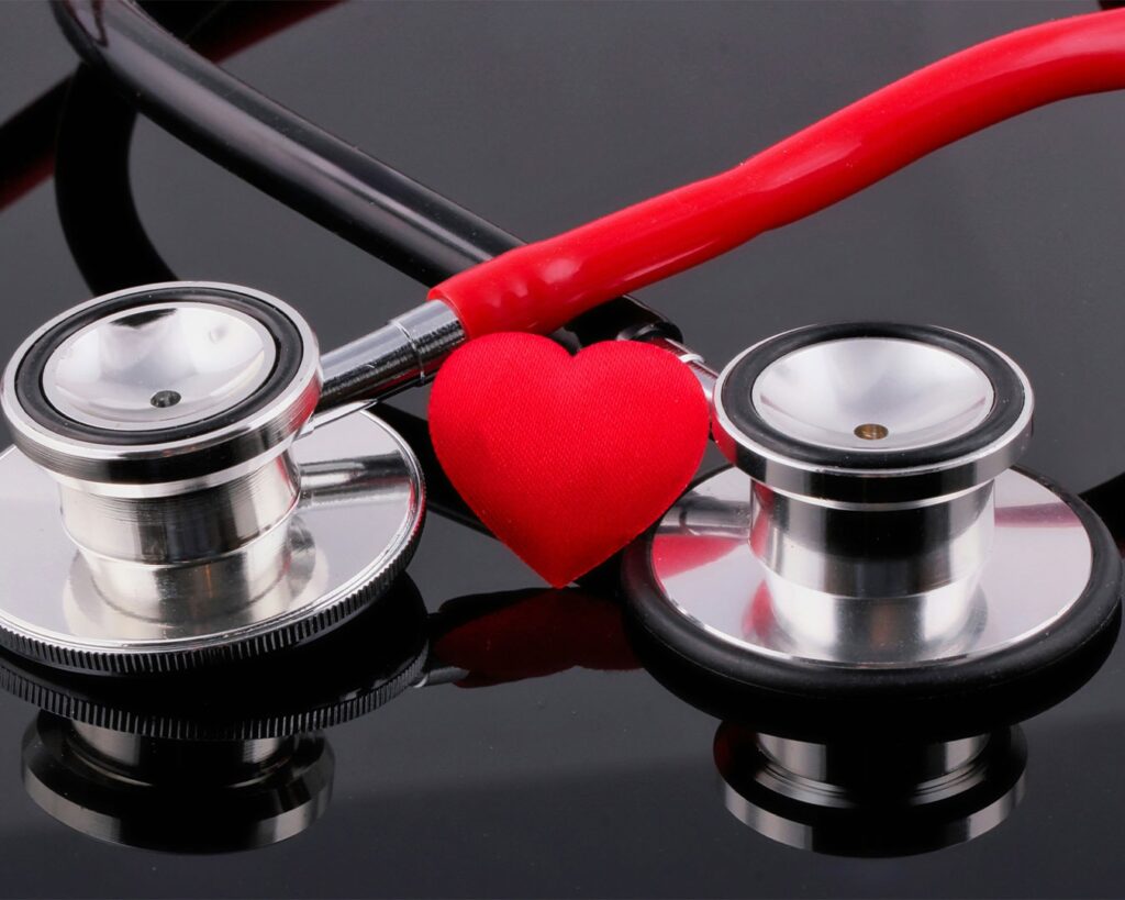 A doctor’s stethoscope placed beside a small heart model on a clean table, symbolising healthcare, heart health, and medical care.