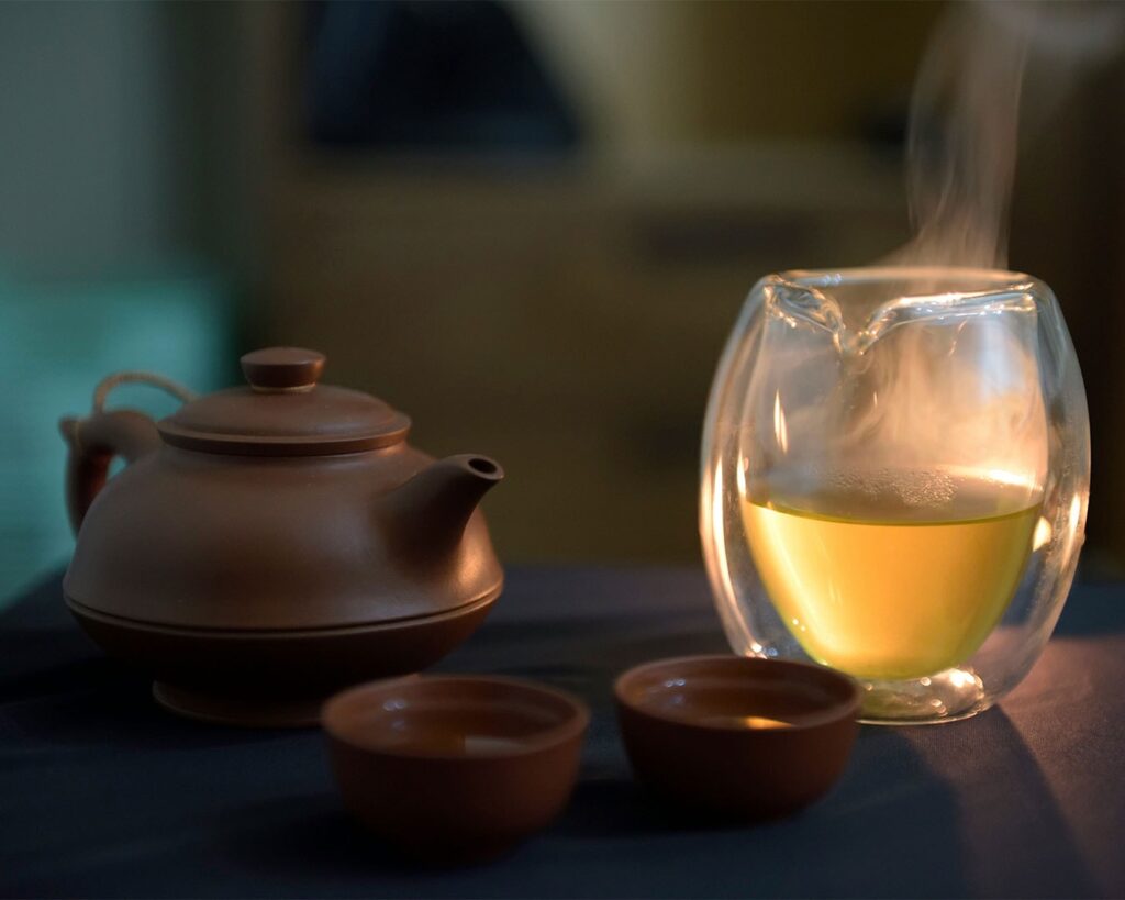 A freshly brewed cup of tea sitting on a saucer, with light steam floating above the surface, highlighting its rich colour and inviting aroma.