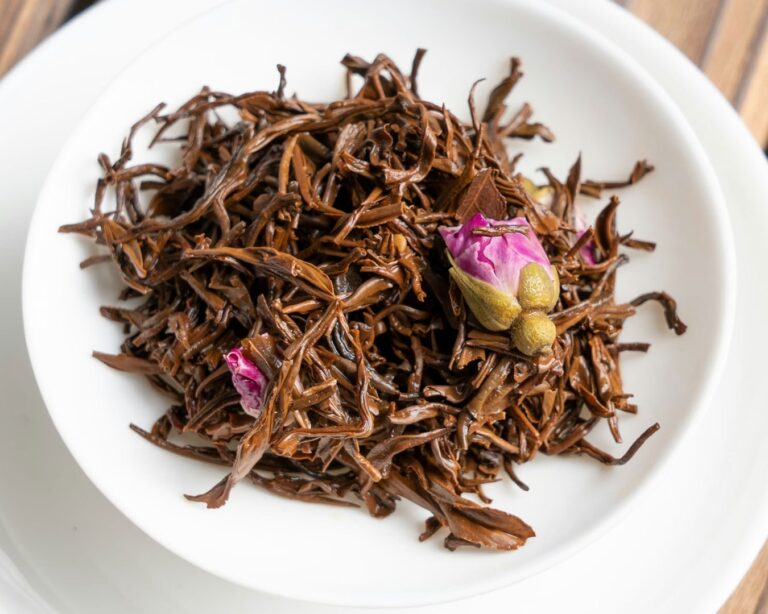 Loose dried tea leaves arranged on a small plate, showing their natural shape and colour before brewing, highlighting the raw beauty of traditional Chinese tea.