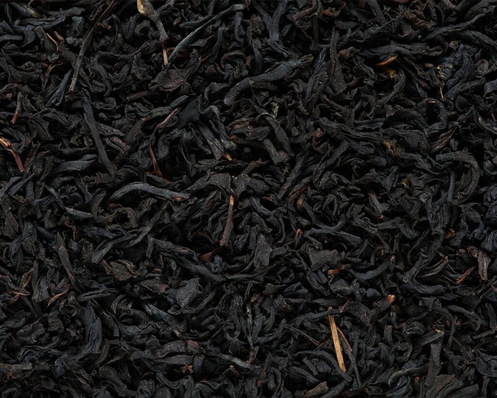 Close-up of dried black tea leaves with curled edges and deep brown tones, showing their rich texture and traditional tea-processing form.