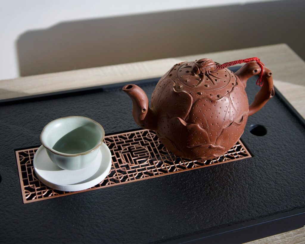 A classic Chinese teapot placed on a tea tray, designed for mindful brewing and preserving heat during steeping.