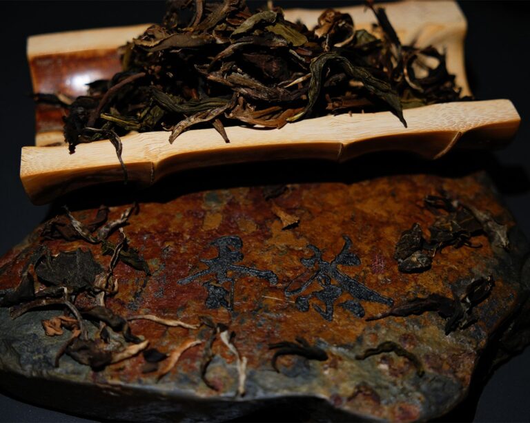 Fresh tea leaves resting on a bamboo tray placed over natural stone, symbolising purity, balance, and the quiet beauty of traditional tea preparation.