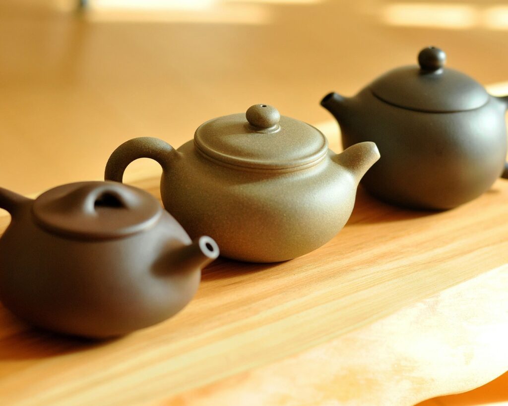A trio of intricately designed Chinese teapots, each embodying centuries of tea-making tradition.