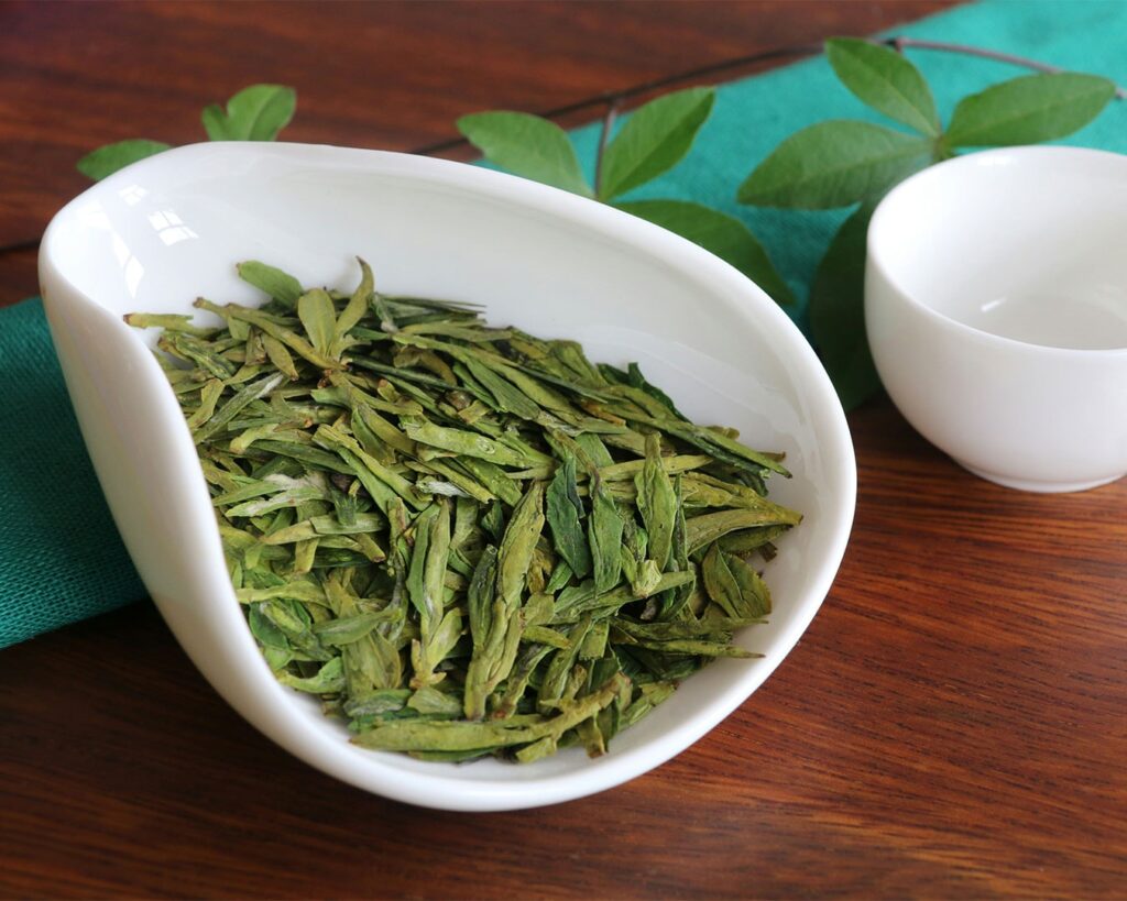 A warm cup of brewed Longjing tea in an elegant teacup, with light green tea colour visible, creating a calm and refined tea-drinking atmosphere.