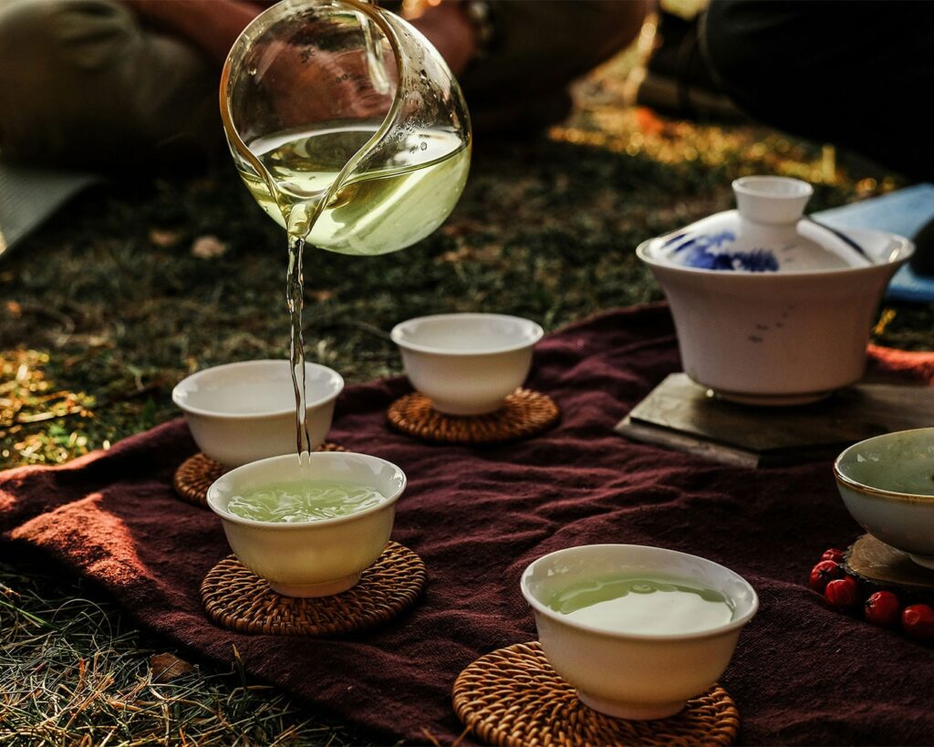 Close-up of tea being poured from a teapot into a cup, showing smooth movement and steam rising from the hot tea.