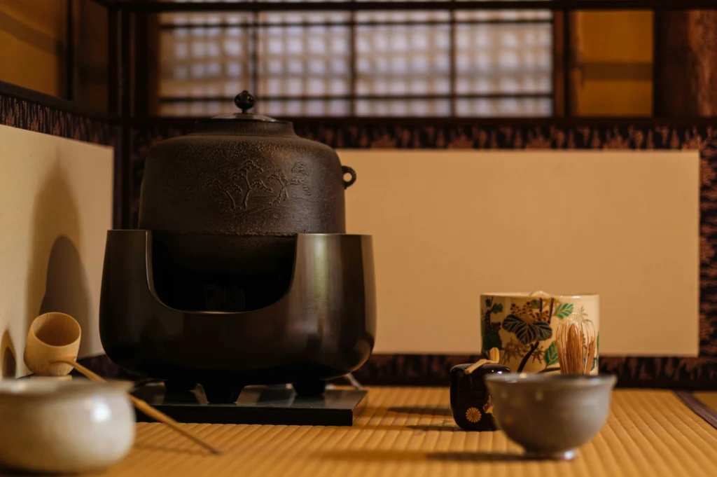 Traditional Japanese tea room with a cast iron kettle, tea bowls, bamboo whisk, and intricate wall paneling, exuding a serene and elegant atmosphere.
