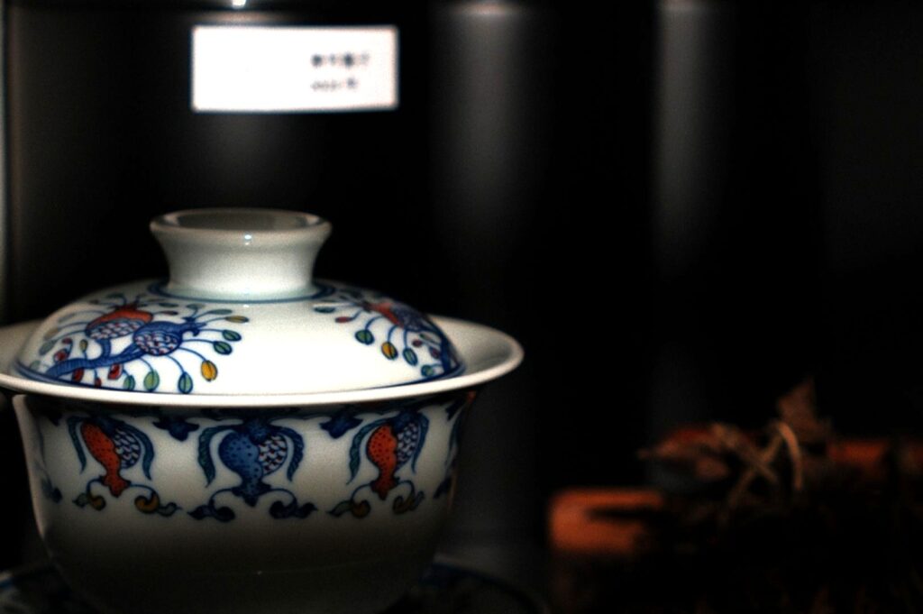 A decorative porcelain tea cup with intricate blue and red designs sits against a soft focus background, creating a serene, elegant atmosphere.