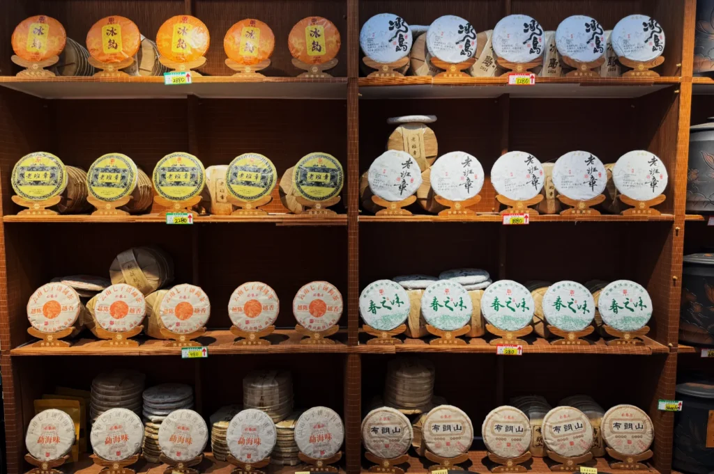 Shelves filled with colorful, round packages of Pu-erh tea, each labeled with intricate designs and Chinese characters, evoke a sense of cultural richness.